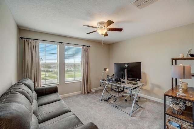 office space featuring light colored carpet, visible vents, a ceiling fan, a textured ceiling, and baseboards