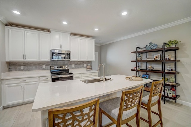 kitchen with a breakfast bar, crown molding, stainless steel appliances, tasteful backsplash, and a sink