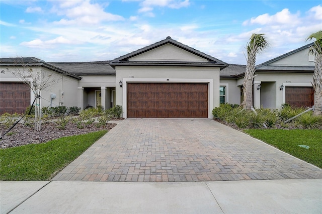 single story home featuring decorative driveway, an attached garage, and stucco siding