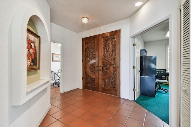 tiled entryway with a textured ceiling