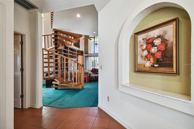 hallway with dark tile flooring, a chandelier, and a textured ceiling