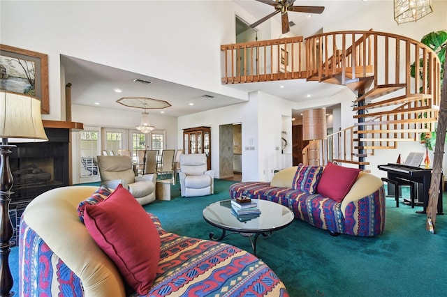 carpeted living room featuring ceiling fan with notable chandelier and a high ceiling