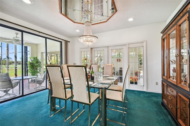 dining space with ceiling fan with notable chandelier, dark colored carpet, and a textured ceiling