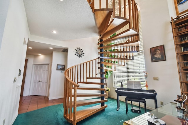 staircase with a textured ceiling and dark carpet