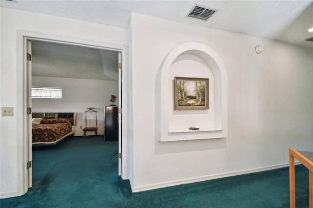 corridor with dark carpet and a textured ceiling