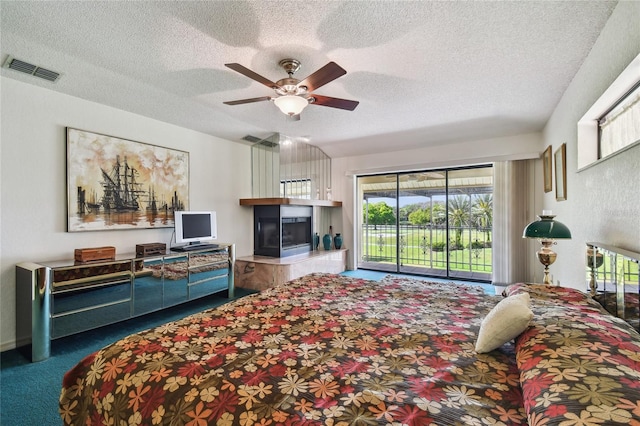 carpeted bedroom with ceiling fan, access to outside, and a textured ceiling