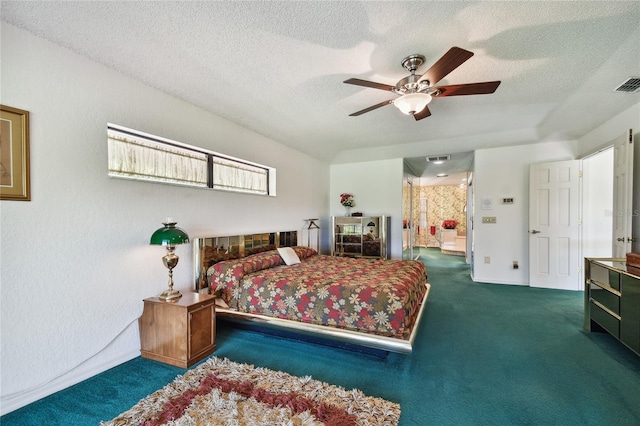 bedroom with a textured ceiling, dark colored carpet, ceiling fan, and connected bathroom