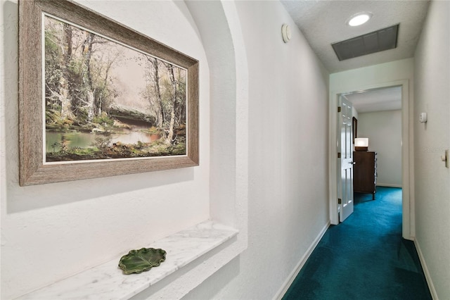 hallway with dark carpet and a wealth of natural light