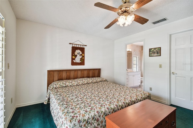 bedroom featuring ceiling fan, dark carpet, connected bathroom, and a textured ceiling