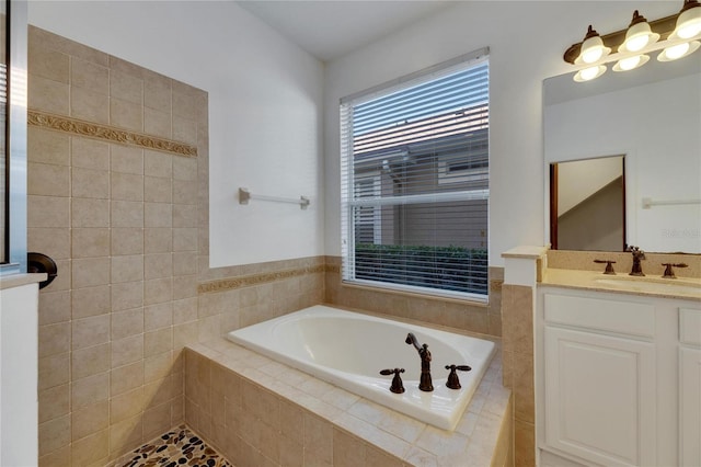 bathroom featuring tiled tub and vanity