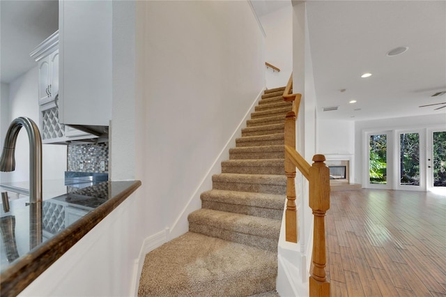 stairway with ceiling fan and hardwood / wood-style flooring