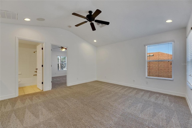 carpeted empty room featuring ceiling fan, a healthy amount of sunlight, and vaulted ceiling