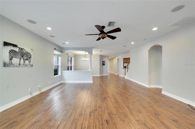 unfurnished living room featuring hardwood / wood-style floors and ceiling fan with notable chandelier