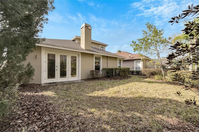 back of property with french doors and a lawn