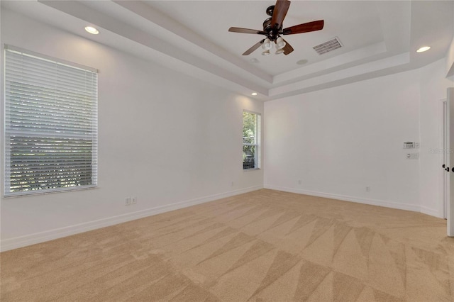 spare room with light carpet, a raised ceiling, and ceiling fan