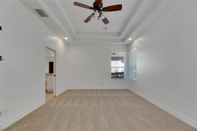 carpeted spare room with a tray ceiling and ceiling fan