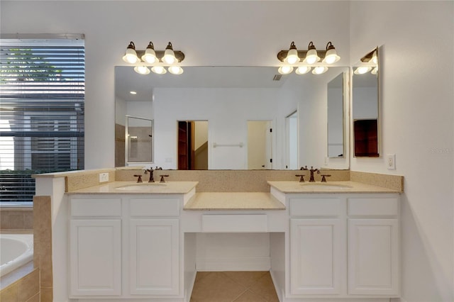 bathroom featuring tile patterned flooring, vanity, and tiled tub