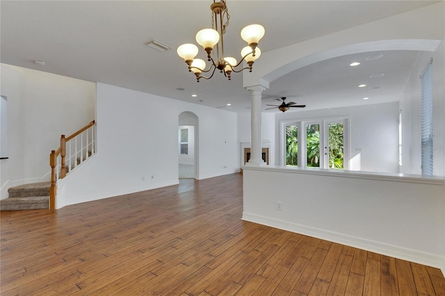 empty room with a fireplace, hardwood / wood-style floors, and ceiling fan with notable chandelier