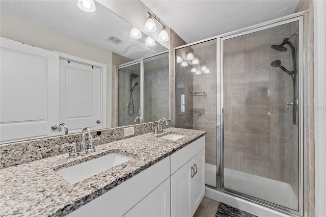 bathroom featuring vanity, a shower with shower door, and a textured ceiling