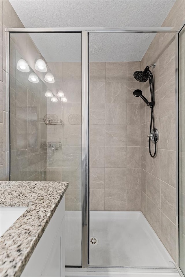 bathroom with vanity, a shower with shower door, and a textured ceiling