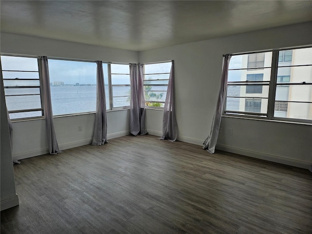 spare room with plenty of natural light, dark wood-type flooring, and a water view