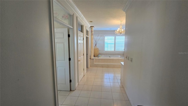 hallway with light tile floors, ornamental molding, and a notable chandelier