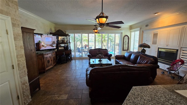 tiled living room with ornamental molding, a textured ceiling, and ceiling fan