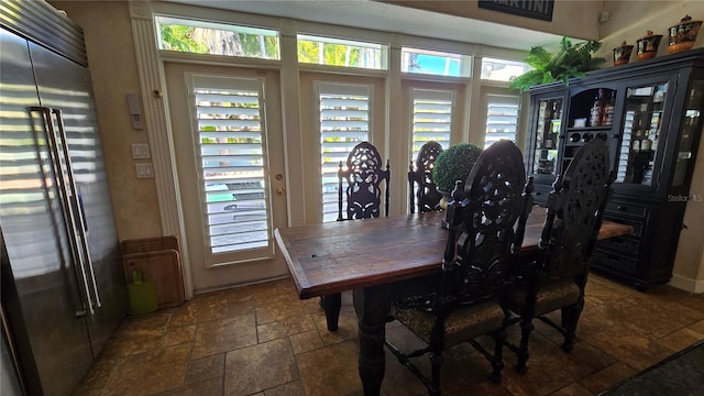 dining room with dark tile floors and a wealth of natural light