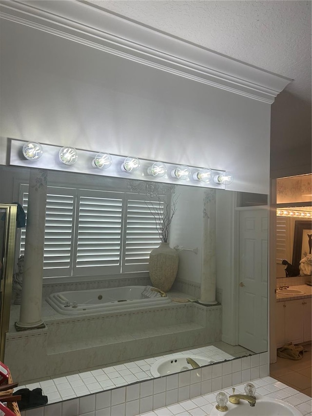 bathroom with tile floors, tiled tub, ornamental molding, and vanity