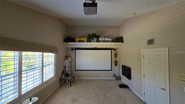 home theater room with plenty of natural light, lofted ceiling, and light colored carpet