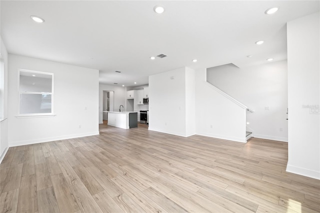 unfurnished living room featuring sink and light hardwood / wood-style flooring