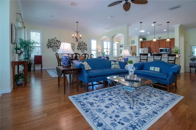 living room featuring a healthy amount of sunlight, ornamental molding, dark hardwood / wood-style floors, and ceiling fan with notable chandelier