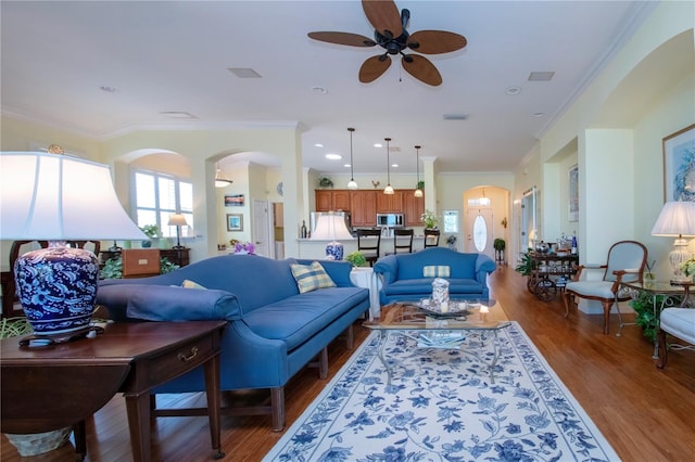 living room with dark hardwood / wood-style floors, ceiling fan, and ornamental molding