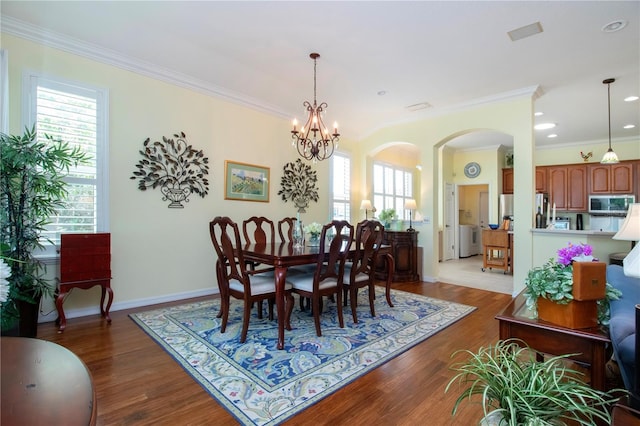 dining area with a notable chandelier, washer / clothes dryer, light hardwood / wood-style flooring, and crown molding