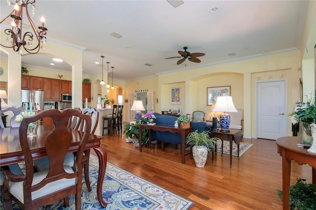 dining space featuring crown molding, light hardwood / wood-style floors, and ceiling fan with notable chandelier