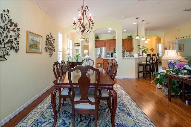 dining area with light hardwood / wood-style floors, ornamental molding, a healthy amount of sunlight, and a chandelier