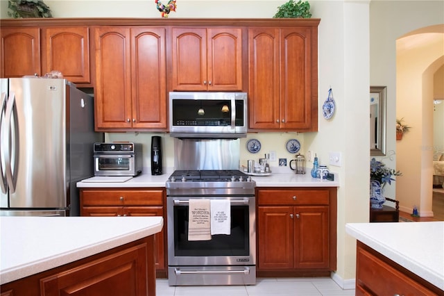 kitchen featuring light tile flooring and appliances with stainless steel finishes