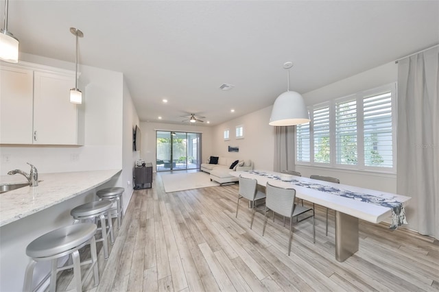 dining area featuring ceiling fan, sink, light wood-type flooring, and a healthy amount of sunlight