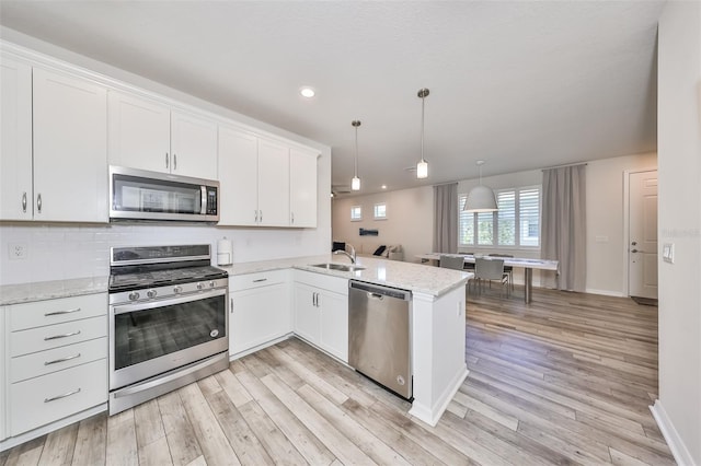 kitchen with white cabinetry, light hardwood / wood-style flooring, appliances with stainless steel finishes, and kitchen peninsula