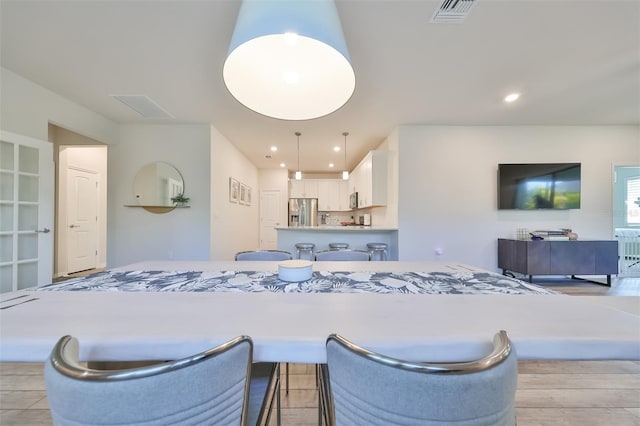 interior space featuring a kitchen breakfast bar, hanging light fixtures, stainless steel refrigerator with ice dispenser, and white cabinetry