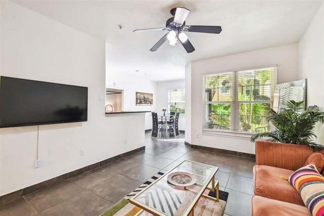 living room with plenty of natural light, dark tile floors, and ceiling fan