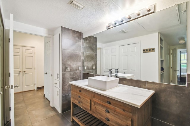 bathroom with tile walls, tile floors, a textured ceiling, and vanity