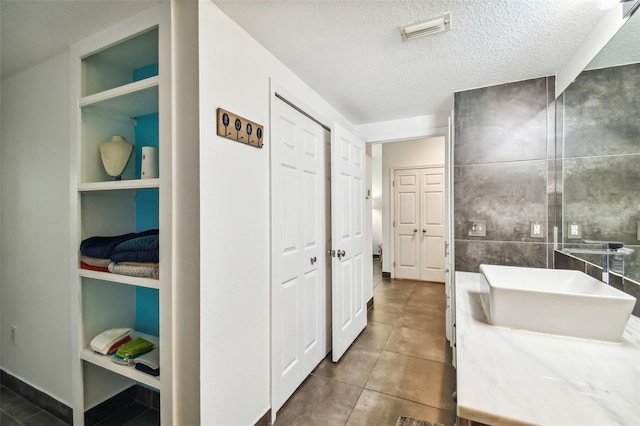 hall featuring built in features, dark tile floors, a textured ceiling, and tile walls