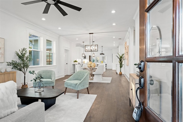 living room with ceiling fan with notable chandelier, dark hardwood / wood-style flooring, and crown molding