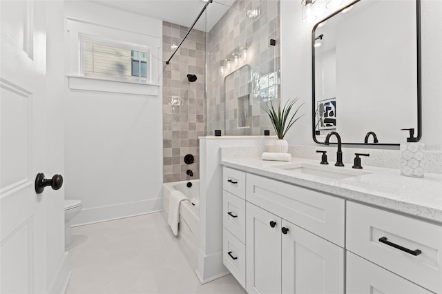 full bathroom featuring tile patterned floors, vanity, tiled shower / bath, and toilet