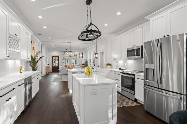 kitchen featuring pendant lighting, dark wood-type flooring, kitchen peninsula, white cabinetry, and stainless steel appliances