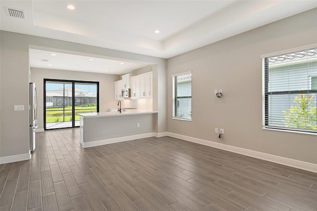 kitchen with white cabinets, stainless steel appliances, tasteful backsplash, sink, and kitchen peninsula