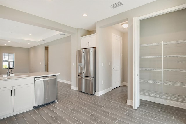 kitchen with appliances with stainless steel finishes, sink, and white cabinetry