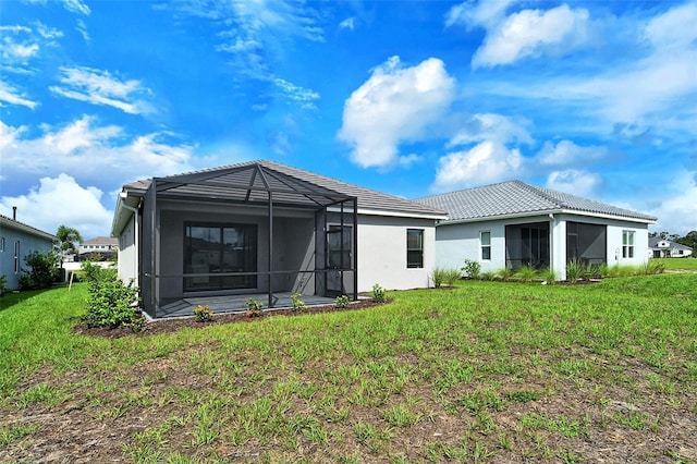 back of property featuring a yard and glass enclosure