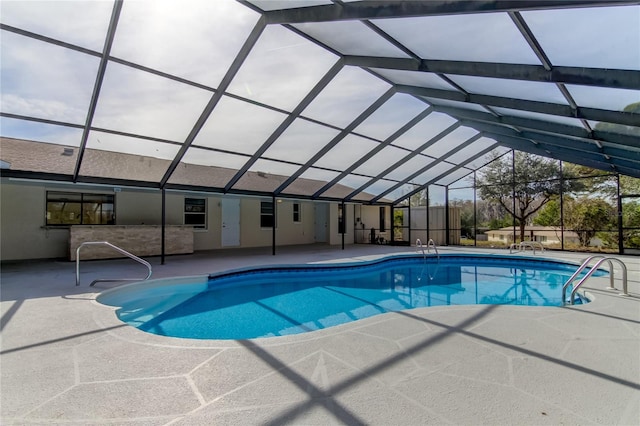 view of pool with glass enclosure and a patio area